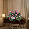 A broad, low casket spray that balances vivid pink roses with soft
