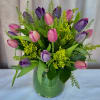 Bright clusters of pink and purple tulips rise from a rounded green