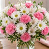 A charming and graceful floral arrangement featuring crisp white daisies, soft pink