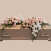 A low, elongated sympathy spray designed to rest across a wooden casket