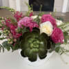 Pink and white roses arranged in a white vase with a large succulent accent