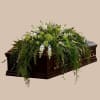 Green and white floral casket spray on a dark wood coffin