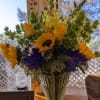 Yellow roses with sunflowers, purple mums, snapdragons and a variety of greenery.