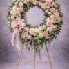A graceful standing wreath designed with soft blush roses, creamy ivory roses