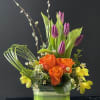Orange roses and purple tulips in a striped glass vase