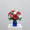 Red and white mixed bouquet in a blue glass vase