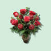 Red roses arranged in a glass vase with decorative red spheres