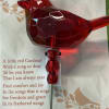 A translucent red cardinal figurine on a slim metal stake offers a