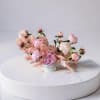 Soft blush peonies and delicate blooms float in a low, airy arrangement