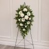 All-white standing spray arranged on a metal easel creates a calm, respectful