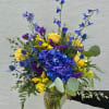 Blue and yellow mixed bouquet in a glass vase