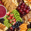 Fruit and snack platter with cookies, cheese, grapes, berries, and dip
