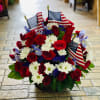 Red roses and white daisies arranged with small American flags