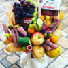 Fruit and snack bouquet with grapes, apples, cheese, salami, and bread