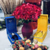 Red rose bouquet in a vase with chocolate-covered strawberries and gift boxes