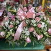A soft, full casket spray in pink, white, and green creates a