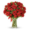 Red roses and carnations in a clear glass vase with a red ribbon