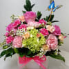 Pink and peach floral arrangement in a white box with a butterfly pick