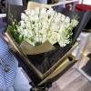Tall bouquet of white roses with green orchid buds wrapped in black and gold paper
