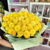Large bouquet of bright yellow roses wrapped in pale mint paper