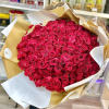 Large bouquet of hot pink roses wrapped in white and gold paper in a flower shop