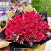 Large bouquet of hot pink roses with purple blooms wrapped in black and gold paper.