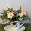 Pastel flower arrangement in a teacup on a saucer