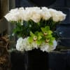 White roses and green orchids in a black vase