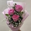 3 roses wrapped on paper with greenery and baby breath 