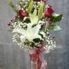 Tall bouquet of white lilies and red roses in a glass vase