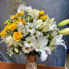 Yellow roses and white lilies in a glass vase with white daisies