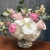Pink and white flowers arranged in a clear glass vase