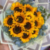 Bouquet of sunflowers wrapped in layered paper with eucalyptus