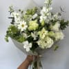 Seasonal wild white flowers arranged into a hand-tied bouquet with filler and