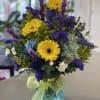 Bright mixed bouquet with yellow gerbera daisies in a blue vase