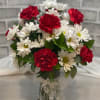 Bouquet of red carnations and white daisies in a glass vase