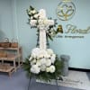White sympathy cross of lilies, roses, chrysanthemums and hydrangea-like blooms with green
