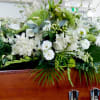 Large white floral spray arranged on a wooden casket