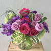 Bouquet of pink and lavender roses with purple flowers in a glass vase