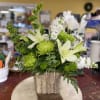Pale white lilies and vivid green chrysanthemums give this Whispering Cottage flower