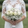 Bride holding a white rose bouquet with baby's breath