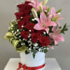 Red roses and pink lilies in a white hatbox with a red ribbon