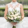 Bride holding a bouquet of white roses and greenery