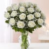 Arrangement of white roses with filler flowers in a clear glass vase