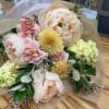 Pastel bouquet with large blush peonies and yellow blooms wrapped in paper