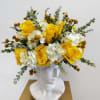 Yellow roses and white hydrangeas arranged in a white bust vase