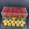 Red roses in a clear acrylic box above gold-wrapped chocolates