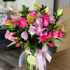 Pink rose bouquet in a clear glass vase with a ribbon