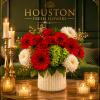 Red and white flower arrangement in a white vase with candles nearby