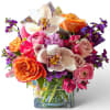 Mixed bouquet with roses, orchids, and purple flowers in a glass vase